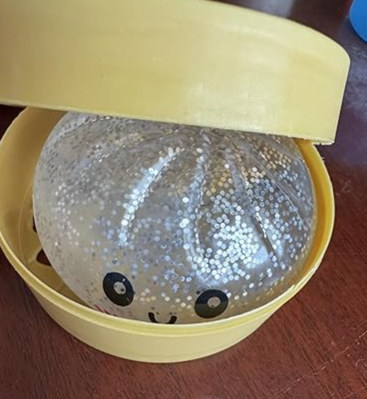 Silver glitter Dumpling Squishy peeking from its steamer box